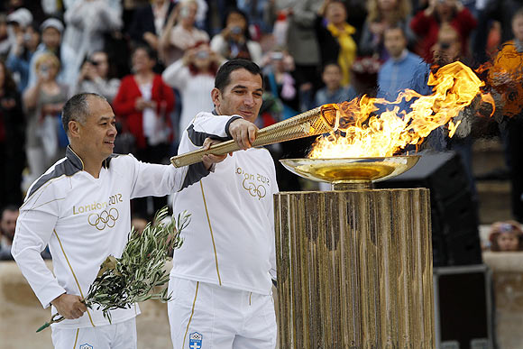 Greek veteran weighlifter Piros Dimas (right) and Chinese gymnast Li Ning light a cauldron with the Olympic Flame inside the marble Panathenaic stadium in Athens