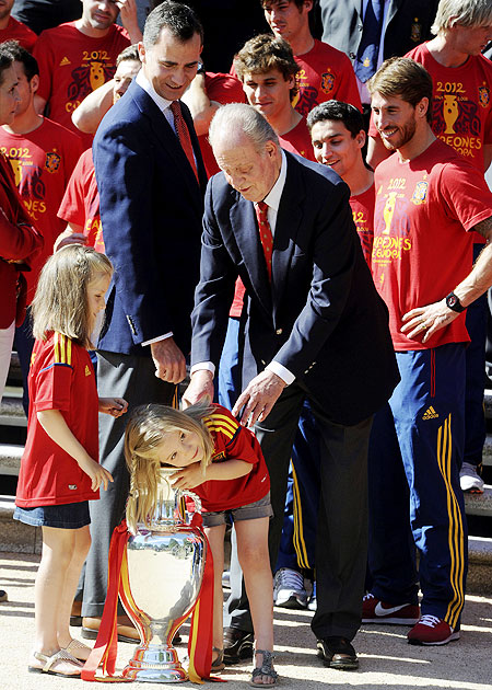 Spain's King Juan Carlos and Crown Prince Felipe (second left) looks at Infanta Sofia (bottom right) as she puts her arm into the Euro 2012 trophy next to Infanta Leonor (left) during a visit of the national soccer team members to Madrid's Zarzuela Palace