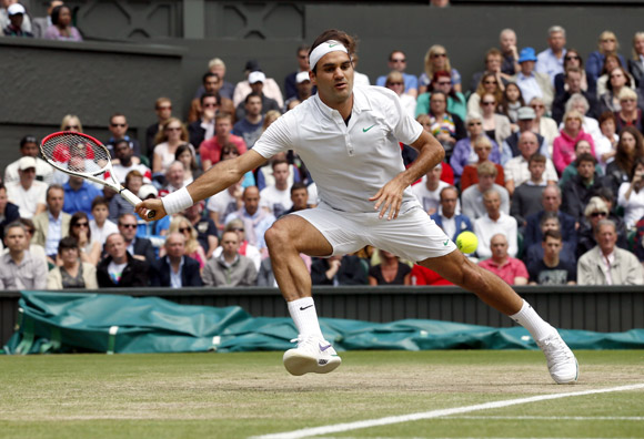 Roger Federer of Switzerland hits a return to Mikhail Youzhny of Russia during their men's quarter-final tennis match at the Wimbledon tennis championships in London