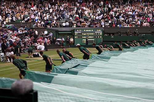 Roger Federer and Andy Murray walk off court as rain delays play and the court is covered during their Men's singles final