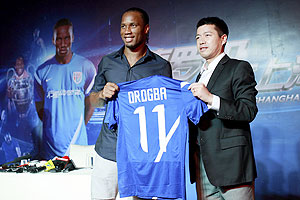 Zhou Jun (right), director of Shanghai Shenhua Football Club, and Didier Drogba hold up a Shanghai Shenhua FC jersey during an unveiling