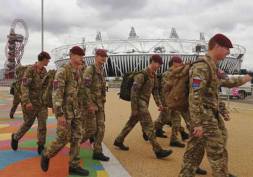 Soldiers pass the Olympic Stadium in the London 2012 Olympic Park in Stratford