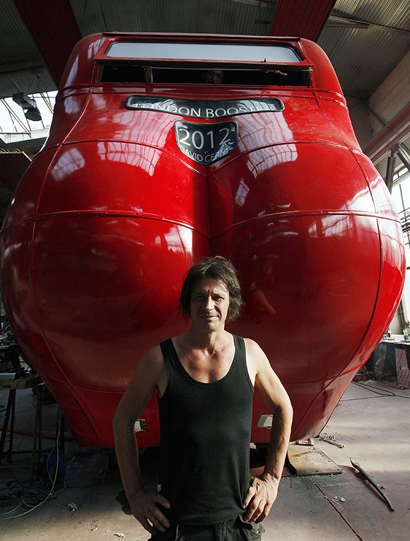 Czech artist David Cerny poses next to a London bus that he has transformed into a robotic sculpture in Prague