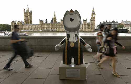 People walk by an Olympic mascot, painted in the likeness of a member of Parliament, across the River Thames