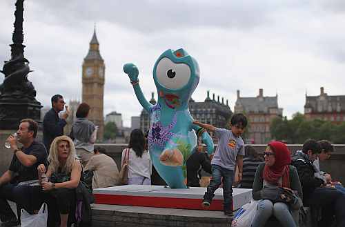 People sit next to a model of a Wenlock, one of the official mascots