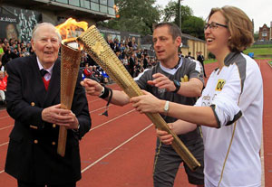 Roger Bannister (left) passes the Olympic flame to Torchbearer Nicola Byrom on the track at Iffley Road Stadium