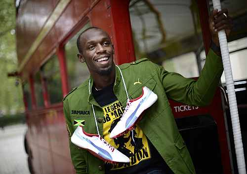 Sprinter Usain Bolt of Jamaica poses during a photo shoot beside a traditional routemaster bus in London