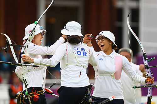 Hyeonju Choi, Bobae Ki and Sung Jin Lee of Korea celebrate victory in the Women's Team Archery Gold medal match between Korea and China