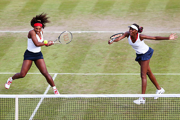 Venus Williams (right) of United States hits a forehand next to her partner Serena Williams during their Women's doubles match against Sorana Cirstea and Simona Halep of Romania