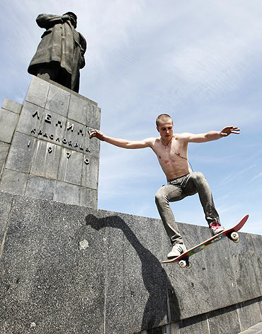 An amateur skateboarder jumps in front of a monument of Vladimir Ilici Lenin, the founder of the former Soviet Union in Krasnoyarsk