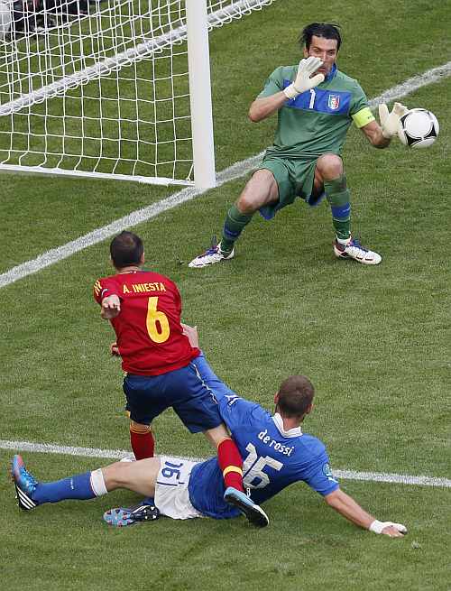 Spain's Andres Iniesta (L) tries to score against Italy's goalkeeper Gianluigi Buffon (R) and Daniele De Rossi during their Group C Euro 2012 soccer match at the PGE Arena