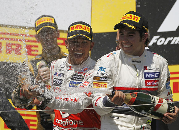 McLaren's Lewis Hamilton (centre) and third placed Sauber's Sergio Perez spray champagne on the podium