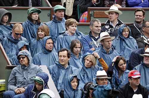 Spectators protect themselves from the rain with raincoats during the men's singles final match during the French Open