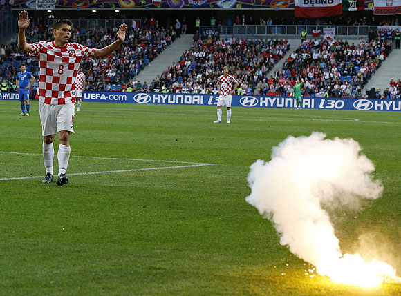 Croatia's Ognjen Vukojevic reacts after a flare is thrown on the pitch
