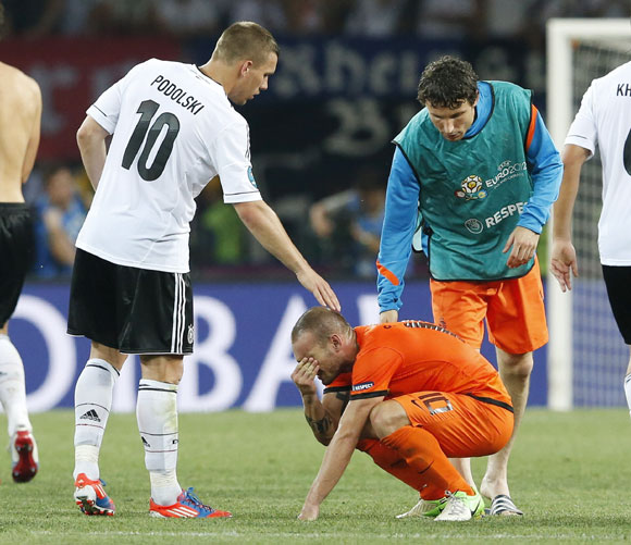 Germany's Lukas Podolski (left) and Netherlands' Mark van Bommel (right) comfort Netherlands' Wesley Sneijder