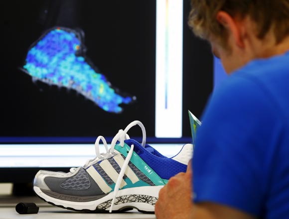 An engineer adjusts test marks on an Adidas running shoe at the Adidas innovation laboratory in Herzogenaurach