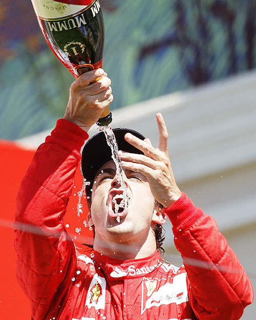 Ferrari Formula One driver Fernando Alonso of Spain drinks champagne