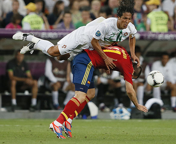 Spain's Alvaro Negredo and Portugal's Bruno Alves (top) fall after an aeriel challenge