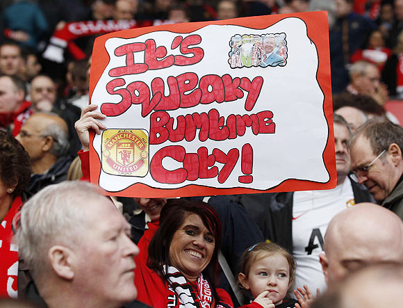 A Manchester United supporter holds a banner during their English Premier League match against West Bromwich Albion at Old Trafford, on Sunday