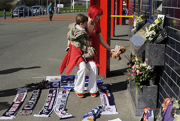 A well-wisher lays a soft toy with a message to Fabrice Muamba at the Reebok stadium in Bolton on Sunday