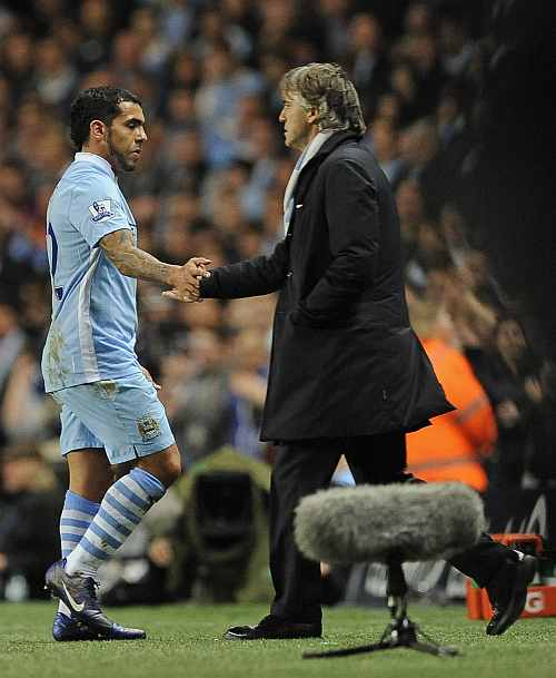 Manchester City's Tevez shakes hands with manager Mancini as he is substituted during their Premier League match at the Etihad stadium