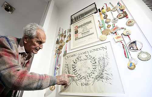 Ottavio Missoni points to the diploma he was given for his participation in the 1948 Olympics in London at his house