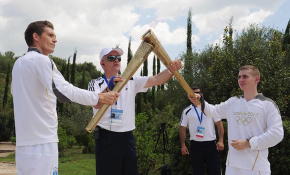 Alex Loukas from Britain lights the London 2012 Olympic Torch from Spyros Gianniotis of Greece during the Lighting Ceremony of the Olympic Flame at Ancient Olympia on May 10, 2012 in Olympia, Greece