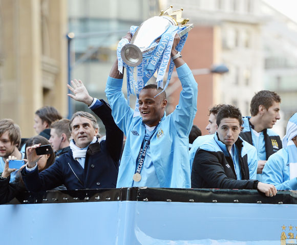 Roberto Mancini the manager of Manchester City stands alongside his captain, Vincent Kompany (C) and Samir Nasri (R) as they parade the Barclays Premier League trophy in front of thousands of fans during their victory parade around the streets of Mancheste