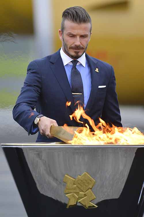 British soccer player and London 2012 Olympic Games ambassador David Beckham lights the Olympic torch with a cauldron after arriving at RNAS Culdrose base near Helston