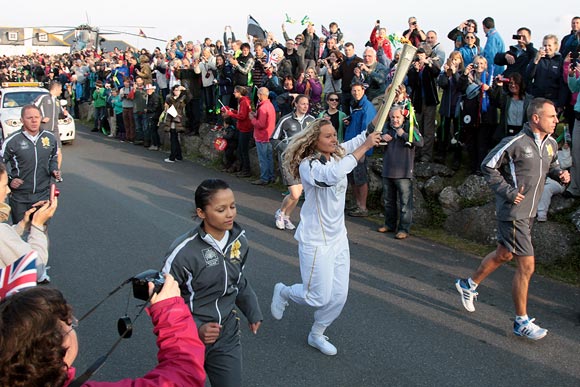 Surfer Tassy Swallow carries the Olympic Flame as it leaves Lands End