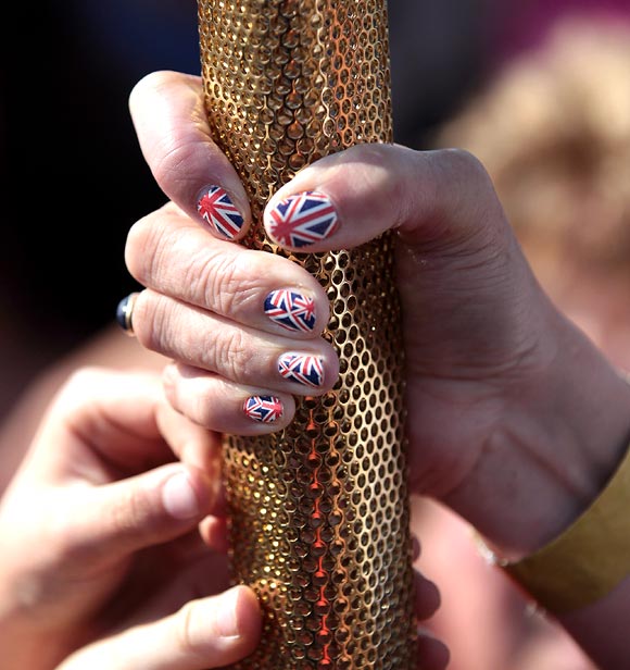 The finger nails of Olympic Flame torchbearer Sarah Blight are decorated in a Union Jack design as she poses for photographs in front of St Michael's Mount