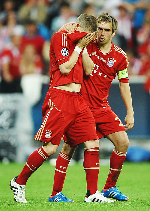 Bastian Schweinsteiger of Bayern Muenchen is comforted by Philipp Lahm