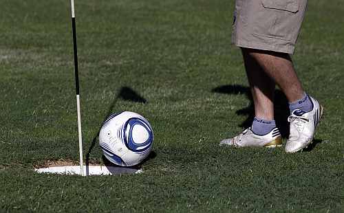 A man kicks a ball into the hole as he competes in a FootGolf tournament