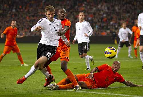 Thomas Mueller of Germany (L) fights for the ball with Bruno Martens Indi (C) and Nigel de Jong