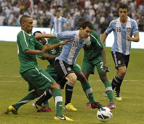Argentina's Lionel Messi (C) challenges Saudi Arabia's Bader Alnakly (L) for the ball during their friendly soccer match
