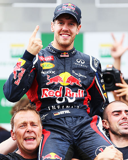 Sebastian Vettel celebrates with teammates on the podium after finishing in sixth position and clinching his third consecutive drivers world championship on Sunday