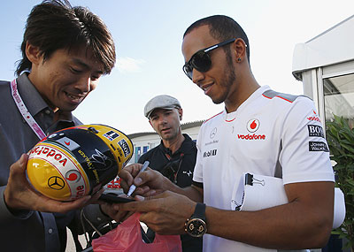 McLaren's Lewis Hamilton signs an autograph for a fan at the Suzuka circuit on Wednesday