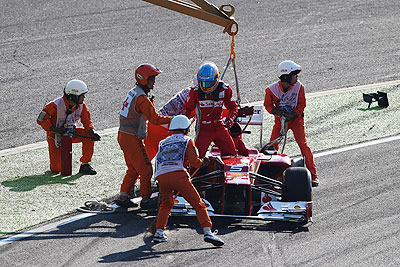 Ferrari's Fernando Alonso is helped from his car by race marshalls after spinning out at the first corner at the start of the Japanese Formula One Grand Prix on Sunday