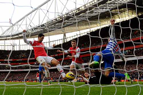 Mikel Arteta of Arsenal pokes the ball past Ryan Nelsen of QPR to score the opening goal during the Barclays Premier League match between Arsenal and QPR