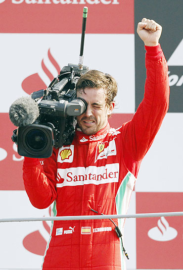 Ferrari's Fernando Alonso films supporters on the podium as he celebrates his third place finish in the Italian F1 Grand Prix at the Monza circuit on Sunday