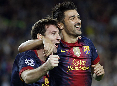 Lionel Messi celebrates with teammate David Villa after scoring