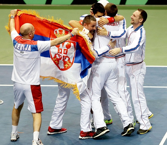 Novak Djokovic of Serbia celebrates his win in the fourth rubber against Sam Querrey with his teammates