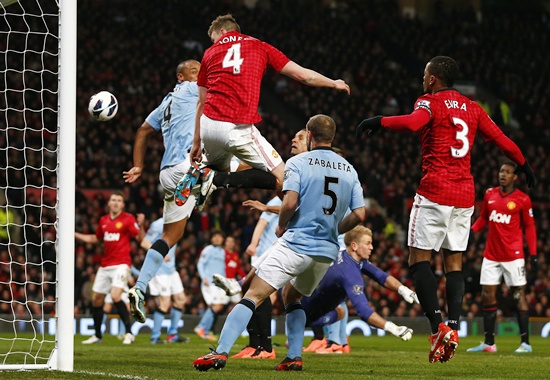 Manchester United's Phil Jones (centre) heads onto the back of Manchester City's Vincent Kompany to score