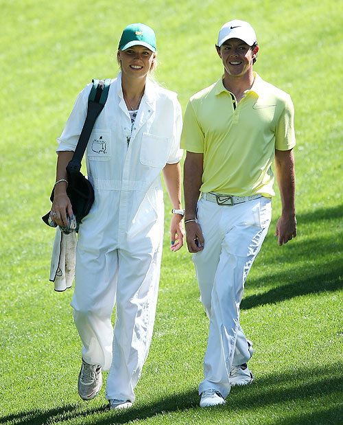Rory McIlroy walks with his caddie and girlfriend Caroline Wozniacki during the Par 3 Contest prior to the start of the 2013 Masters Tournament at Augusta National Golf Club