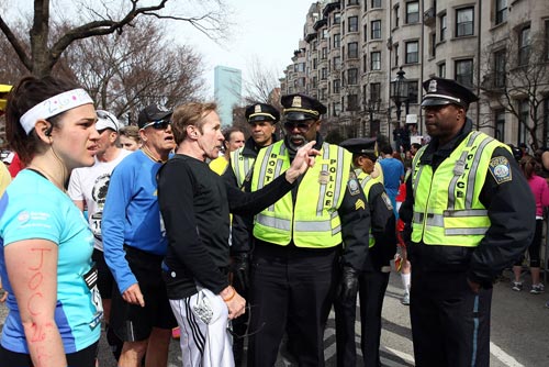 Runners talk to Boston Police near Kenmore Square after two bombs exploded during the 117th Boston Marathon