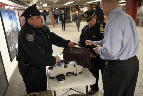 Police check a subway passenger's bag at Penn Station