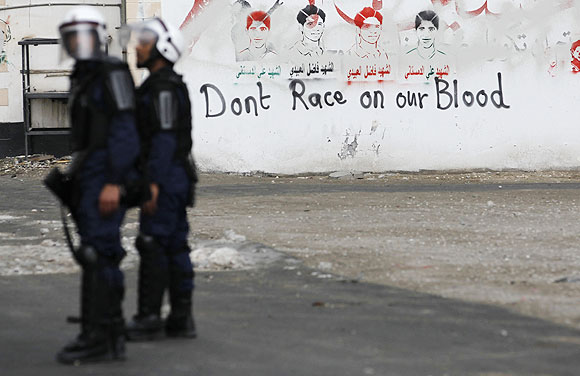 Riot police officers stand near an anti-Formula One graffiti during an anti-government protest in the village of Diraz west of Manama on Friday