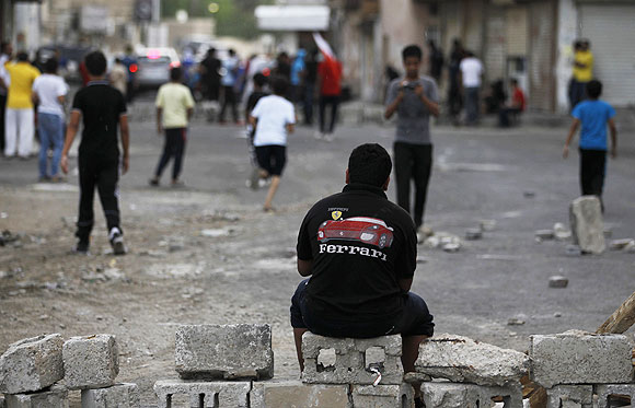 A protester wearing a Ferrari t-shirt sits on a block during an anti-government demonstration in the village of Diraz west of Manama on Thursday