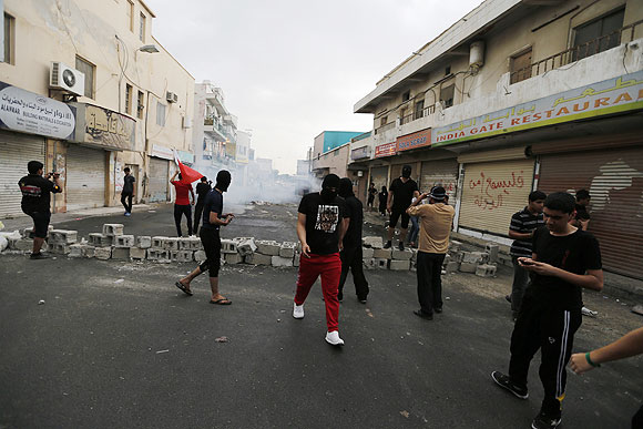 Anti-government protesters stand in front of a teargas cloud fired by riot police during a demonstration in the village of Diraz west of Manama on Thursday