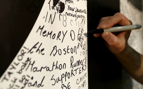 People write on a wall of encouragement, including messages to victims of the Boston bombing